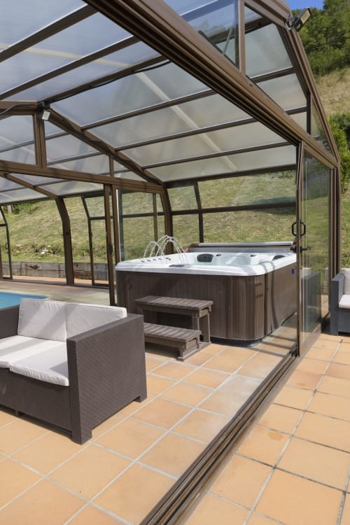 Terraza con bañera de hidromasaje cubierta en Casa Rural Posada Real de Pajares, con zona de descanso y vistas a la montaña