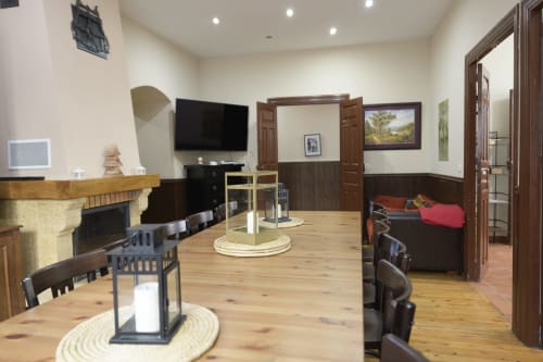 Amplio salón con suelos de madera, chimenea, TV y zona de comedor en Casa Rural Posada Real de Pajares