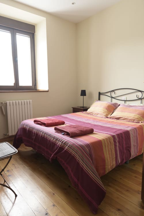 Habitación de Casa Rural Posada Real de Pajares con ropa de cama a rayas rosa, cabecero metálico y vistas a la montaña desde la ventana