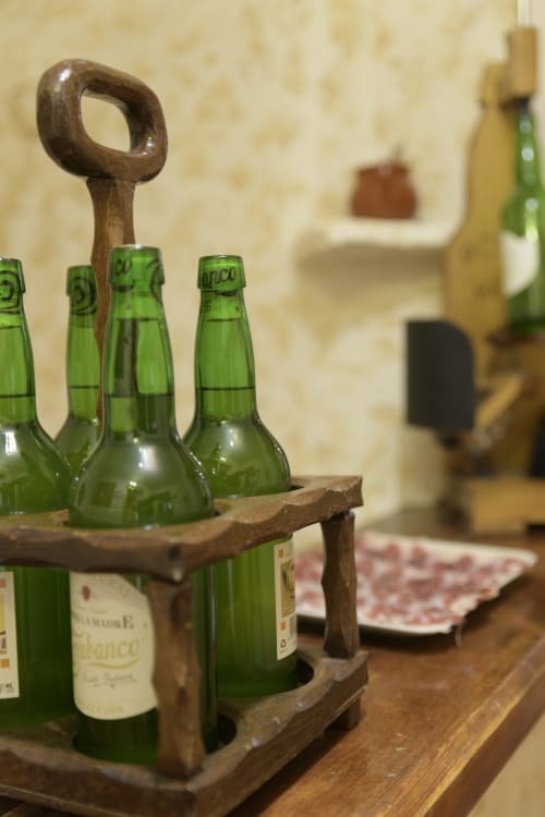 Portador de botellas de cerveza de madera con botellas verdes sobre la mesa en Casa Rural Posada Real de Pajares