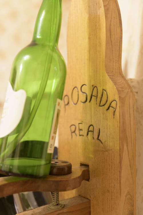 Botella de vino verde en soporte de madera en Casa Rural Posada Real de Pajares, apartamento rural con vistas a la montaña en España