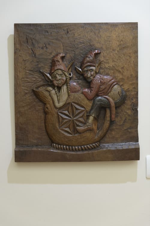 Panel de relieve en madera tallada con dos figuras de bufones en una vasija decorativa de Casa Rural Posada Real de Pajares