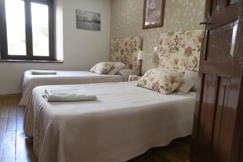 Acogedora habitación en Casa Rural Posada Real de Pajares con camas gemelas, cabeceros florales y vistas a la montaña