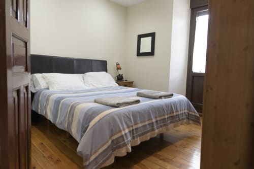 Dormitorio con ropa de cama de rayas azules y beige, cabecero negro, suelo de madera y vistas a la montaña en Casa Rural Posada Real de
