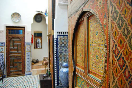 Intérieur traditionnel d'un riad marocain à Fès avec portes en bois sculpté ouvragé et zellige coloré