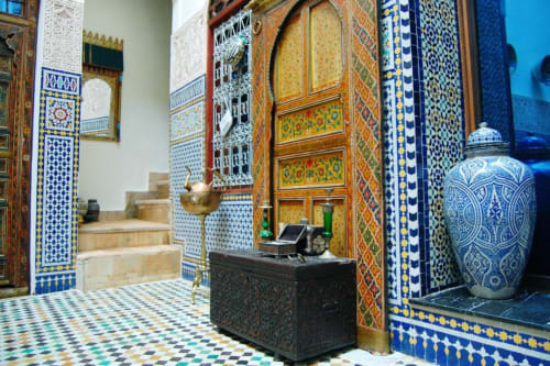 Intérieur majestueux du riad marocain avec zellige bleu et or, portes en bois sculpté et décoration traditionnelle au Riad Fes Aicha