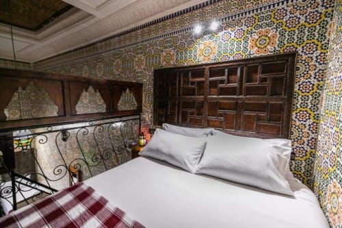Chambre marocaine raffinée au Riad Fès Aïcha avec zelliges, portes en bois sculpté et ferronneries à Fès