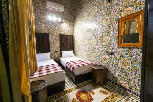 Chambre twin au Riad Fes Aicha à Fès avec zellige marocain traditionnel et lits à couvertures rouge et blanc