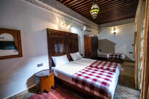 Chambre twin du Riad Fes Aicha à Fès avec décor traditionnel, couvertures écossaises rouges et plafond orné