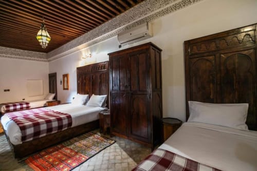 Chambre traditionnelle au Riad Fes Aicha à Fès avec lits jumeaux, mobilier en bois foncé et décoration marocaine