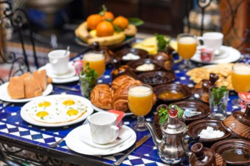 Petit-déjeuner marocain traditionnel au Riad Fes Aicha avec œufs, pâtisseries, oranges fraiches et thé à la menthe à Fès