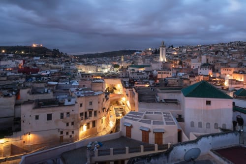 Riad Fes Aicha à Fès, Maroc au crépuscule avec bâtiments traditionnels illuminés et paysage urbain de la médina