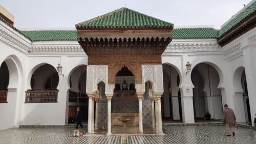 Cour du Riad Fes Aicha à Fès avec arches marocaines, toit de zellige vert et fontaine ornementale