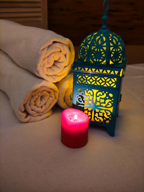 Équipements spa au Riad Fes Aicha : serviettes roulées, lanterne marocaine décorée et bougie allumée dans l'hôtel de Fès