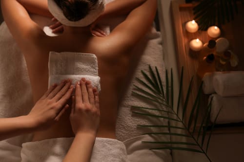 Soin spa et massage au Riad Fes Aicha avec serviettes chaudes, bougies et feuilles de palmier à Fès, Maroc
