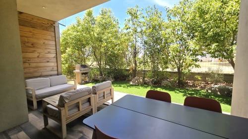 Terrasse de l'appartement Lantana avec table à manger, canapé en bois et vue sur le jardin à Lecci