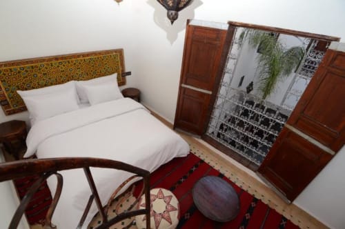 Chambre double de style marocain au Cèdre d'Argent à Fès avec tête de lit ornementale, literie blanche et décoration traditionnelle