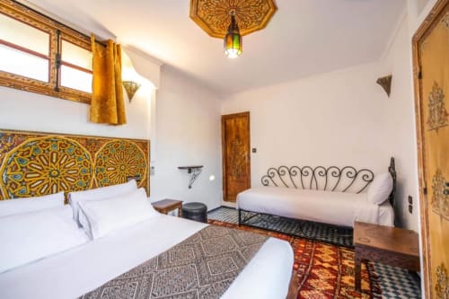 Chambre double de luxe au Cèdre d'Argent, Fès avec têtes de lit marocaines ornementées et draps blancs