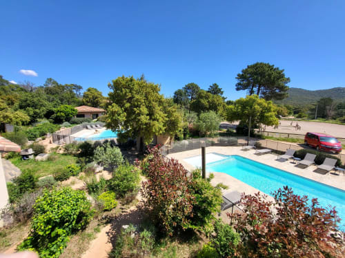 Vue aérienne des piscines et jardins du Domaine Lantana à Lecci avec transats, espaces verts luxuriants et collines sous ciel bleu