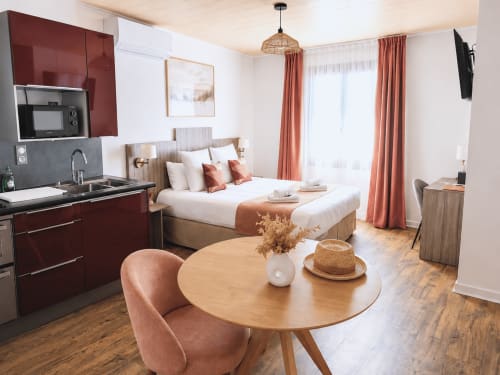 Suite moderne à la Maison des Croisades avec kitchenette équipée, lit, table à manger et accents en terre cuite
