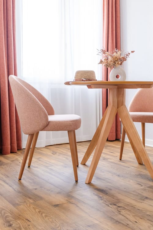 Zone de détente de la suite moderne à la Maison des Croisades avec table en bois, fauteuil capitonné et rideaux ocre