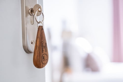Clé de chambre en bois aux couleurs de la Maison des Croisades accrochée à une serrure murale de l'hôtel d'Aigues-Mortes