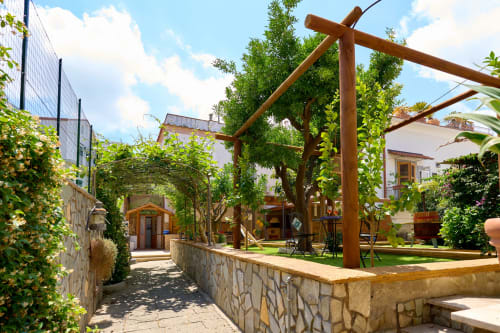 Lemon Garden Escape villa at Sorrento Sea View with wooden pergola, lush greenery, stone courtyard, and Mediterranean
