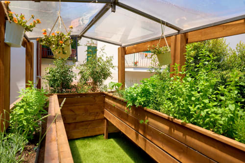 The Lemon Garden Escape villa greenhouse with wooden raised garden beds, hanging planters with flowers, and mountain views at