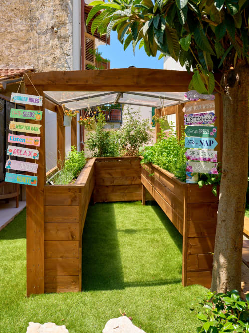 Wooden garden pergola with raised planters and colorful garden signs at Sorrento Sea View villa in Piano di Sorrento