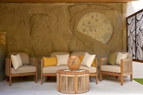 Wooden lounge seating with cushions in Sorrento villa garden, featuring decorative moon mural and woven accent table