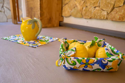 Yellow lemons in decorative fabric bowl with ceramic lemon pitcher in Sorrento villa room décor