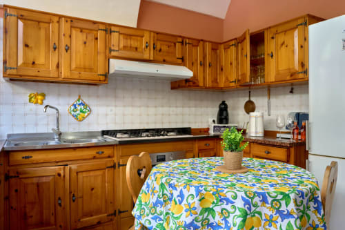 Rustic pine kitchen with wooden cabinets, colorful lemon tablecloth, and white subway tile backsplash in The Lemon Garden