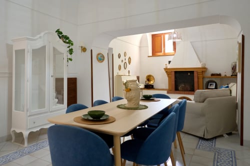 Bright dining room in The Lemon Garden Escape villa, Sorrento, with blue chairs, wooden table, fireplace, and garden view