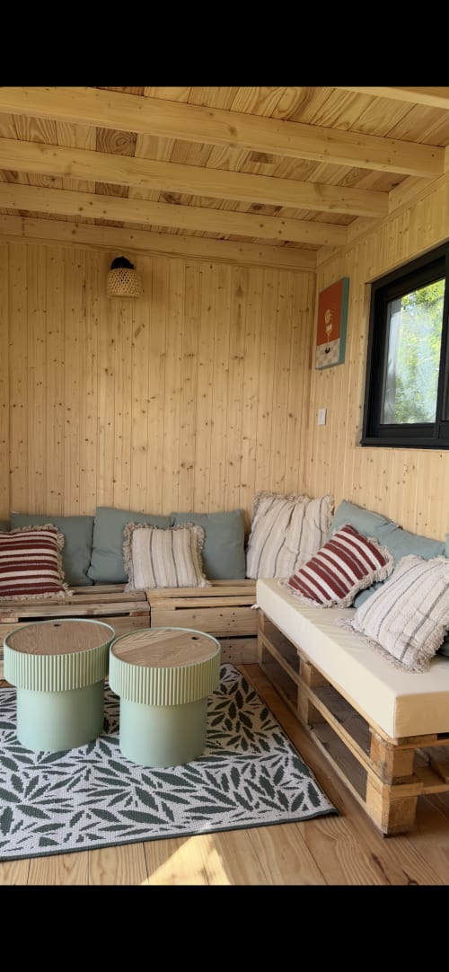 Chambre chaleureuse en bois à Foudre Insolite avec lit, coin détente, coussins et vue sur le jardin