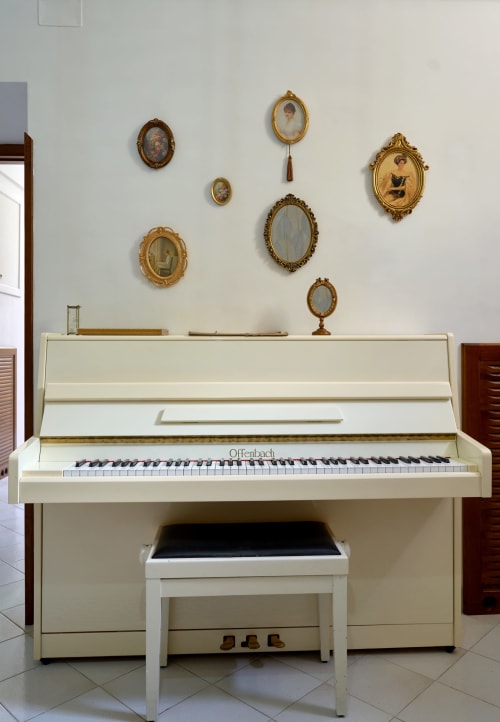 Cream Offenbach piano with bench in The Lemon Garden Escape villa at Sorrento Sea View, framed by ornate gold portrait frames