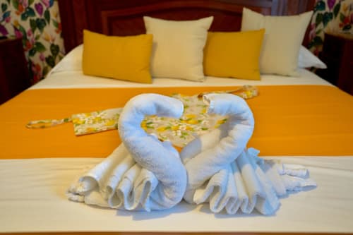White towel swans on bed at Sorrento Sea View villa with yellow pillows and garden-view decor
