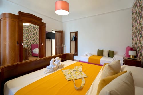 The Lemon Garden Escape villa bedroom at Sorrento Sea View with twin beds, yellow runner, wooden wardrobe, and floral