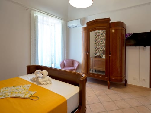 Bright bedroom at Sorrento Sea View villa with wooden furniture, yellow bedding, pink armchair, and garden views