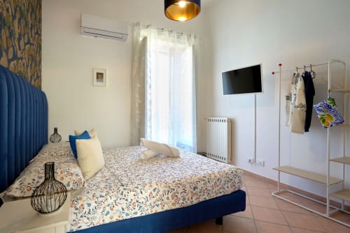 Modern bedroom at Sorrento Sea View with blue bed, flat-screen TV, garden view balcony, and white clothing rack