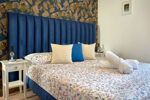 Elegant bedroom in The Lemon Garden Escape villa at Sorrento Sea View with blue pleated headboard, floral bedding, and garden