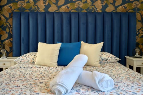Luxurious bedroom with blue velvet headboard, patterned bedding, and rolled towels at Sorrento Sea View villa