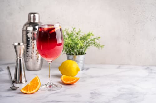 Cóctel artesanal con cítricos frescos en Hotel Boutique Zahara, Cádiz, con herramientas de coctelería y plantas aromáticas sobre mostrador de mármol