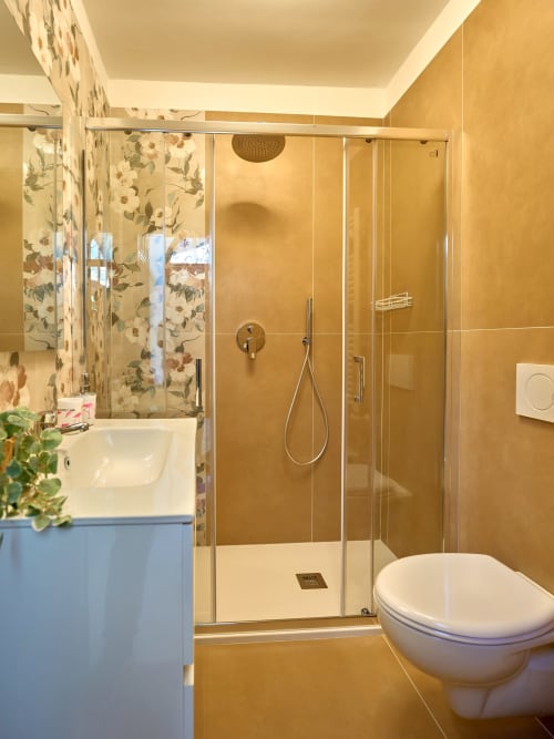 Modern bathroom with walk-in shower, golden tiles, white sink, and toilet at Sorrento Sea View villa