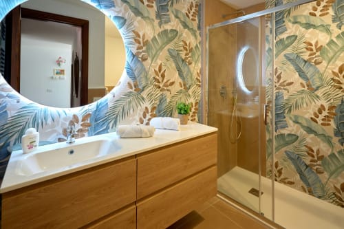 Modern bathroom in The Lemon Garden Escape villa at Sorrento Sea View with tropical wallpaper, wooden vanity, and walk-in
