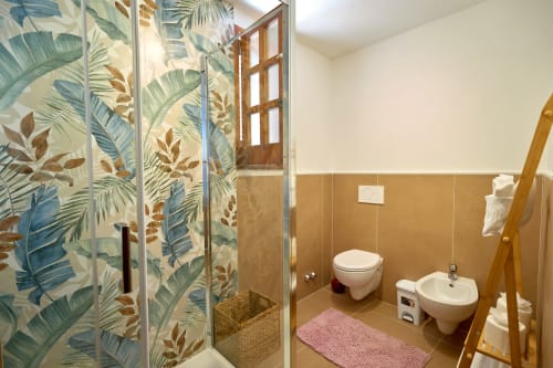 Modern bathroom with tropical leaf shower enclosure, bidet, toilet, and sink at Sorrento Sea View villa