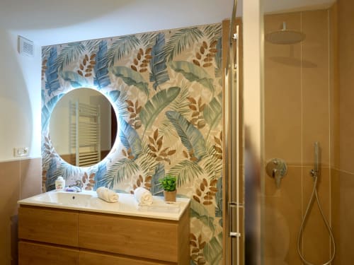 Modern bathroom with tropical leaf wallpaper, illuminated round mirror, wooden vanity, and walk-in shower at Sorrento Sea