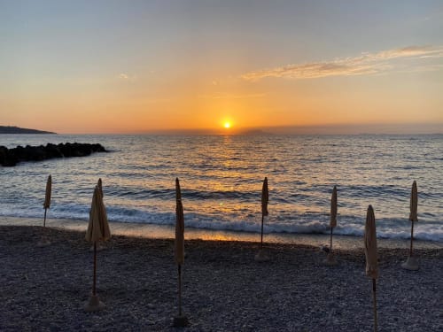 Sunset over Mediterranean Sea at Sorrento beach with closed umbrellas