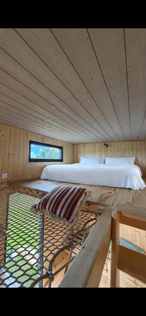 Chambre moderne en bois à Foudre Insolite avec lit blanc, plafond mansardé et vue sur le jardin