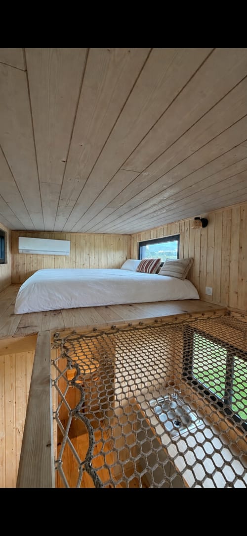 Chambre mansardée aux murs et plafond en bois à Foudre Insolite, lit queen-size, fenêtres, mezzanine avec filet de sécurité