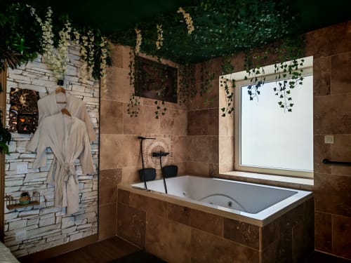 Salle de bain luxueuse de la chambre Love Room à L'expérience avec bain à remous, lierre suspendu, vue montagne et finitions en carrelage brun.